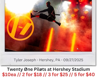 May include: A live concert photo featuring Tyler Joseph of Twenty Øne Pilots mid-air, with a large yellow and black logo in the background. The stage is lit with red and orange lights. Text on the photo reads "Twenty Øne Piløts at Hershey Stadium".