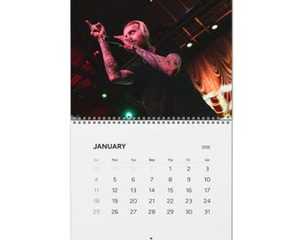 May include: A 2026 calendar featuring a live performance image. The image shows a person with tattoos, holding a microphone. The calendar displays the month of January with the days of the week and dates.