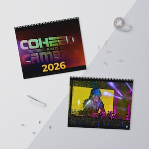 Puede incluir: Dos calendarios encuadernados en espiral. El calendario superior presenta el texto "COHEED AND CAMBRIA 2026" en una fuente degradada. El calendario inferior muestra una escena de concierto con un artista en el escenario, iluminado por luces, frente a una multitud.