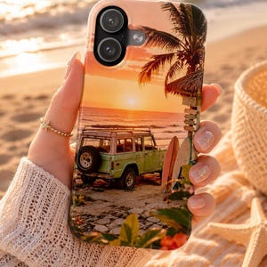 Puede incluir: Una funda para smartphone con una escena de playa al atardecer, que muestra un SUV vintage de color verde claro aparcado en la arena, tablas de surf apoyadas en una palmera y una vista del océano bajo un cielo naranja y amarillo.