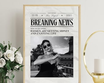 May include: A framed print with the headline "BREAKING NEWS" and the text "WOMEN ARE GETTING MONEY AND ENJOYING LIFE." The image features a black and white photo of a woman holding a glass, with a gold frame.