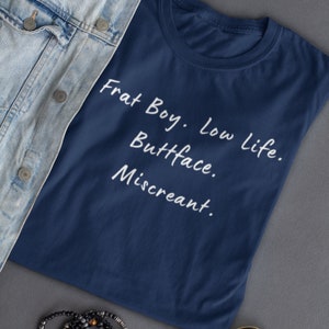 Puede incluir: Una camiseta azul marino con texto blanco que dice "Frat Boy. Low Life. Buttface. Miscreant."