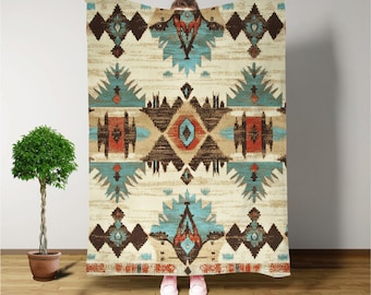 May include: A cream-colored throw blanket with a geometric pattern in shades of brown, blue, and red. The pattern features a central diamond shape with smaller diamonds and triangles surrounding it.
