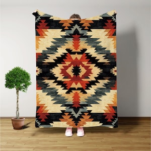 May include: A geometric patterned throw blanket with a black, red, orange, and blue design. The blanket has a southwestern style.