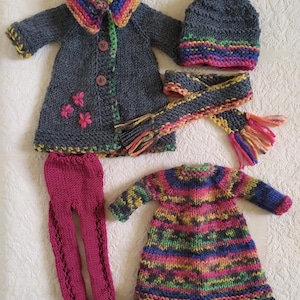 May include: A set of knitted doll clothes in grey, pink, and multi-colored stripes. The set includes a coat, hat, scarf, dress, and leggings.