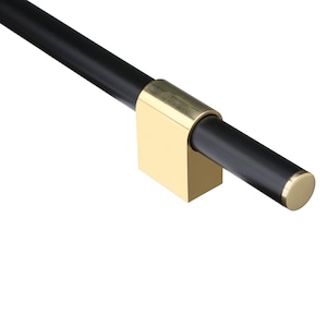 May include: A black cabinet pull with a gold-colored rectangular bracket and end cap. The pull is a cylindrical rod, and the bracket is mounted at a right angle. The hardware is set against a white background.