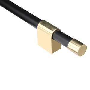 May include: A modern cabinet pull with a black cylindrical handle and gold-toned accents. The pull features a square base and a rounded end cap, creating a sleek, minimalist design. The hardware is set against a white background.