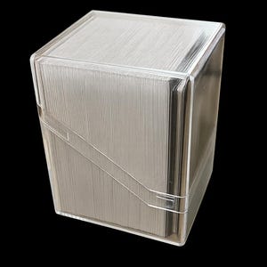 May include: A clear, rectangular card storage box with a lid. The box is made of transparent plastic and contains a stack of cards. The box has a clean, modern design, and is set against a black background.
