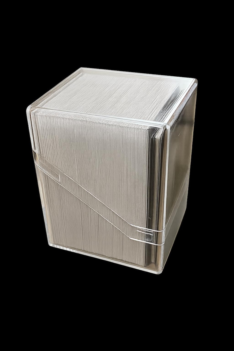 May include: A clear, rectangular card storage box with a lid. The box is made of transparent plastic and contains a stack of cards. The box has a clean, modern design, and is set against a black background.