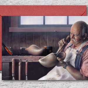 May include: A man in a workshop, wearing a white apron and red and blue striped shirt, is carefully carving a wooden shoe with a chisel. He is surrounded by tools and other wooden shoes.