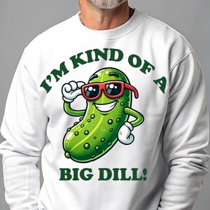 Może przedstawiać: Biała bluza z zielonym kresk&oacute;wkowym og&oacute;rkiem w okularach przeciwsłonecznych i napisem "I'm kind of a big dill!"