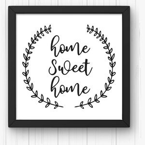 May include: Black and white framed print with a wreath of leaves surrounding the text "home sweet home".