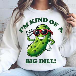 Może przedstawiać: Biała bluza z zielonym kresk&oacute;wkowym og&oacute;rkiem w okularach przeciwsłonecznych i tekstem "I'm kind of a big dill!"