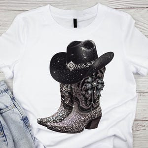 May include: White t-shirt with a black cowboy hat and sparkly silver boots. The hat has rhinestones and a black bow. The boots have a black bow and rhinestones.