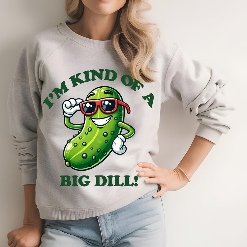 Może przedstawiać: Szara bluza z zielonym kresk&oacute;wkowym og&oacute;rkiem w okularach przeciwsłonecznych i napisem "I'm kind of a big dill!"