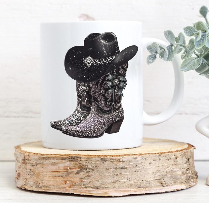 May include: White ceramic mug with a black cowboy hat and boots design. The boots and hat are covered in rhinestones.