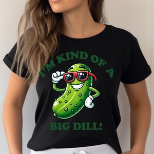 Może przedstawiać: Czarny T-shirt z zielonym kresk&oacute;wkowym og&oacute;rkiem w okularach przeciwsłonecznych i tekstem "Jestem trochę dużym og&oacute;rkiem!"