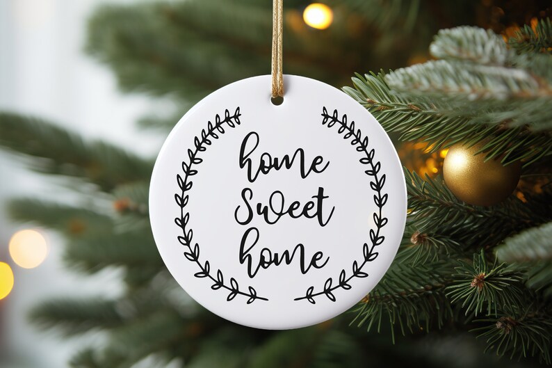 May include: White round ceramic ornament with a black wreath design and the text "home sweet home" in a cursive font.