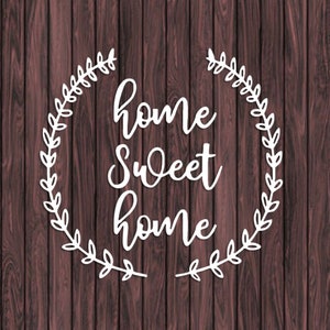 May include: White text on a brown wood background reads "home sweet home" in a cursive font. The text is surrounded by a white wreath of leaves.