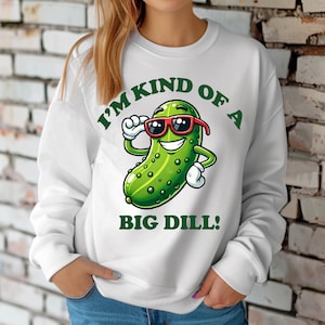 Może przedstawiać: Biała bluza z zielonym kresk&oacute;wkowym og&oacute;rkiem w okularach przeciwsłonecznych i tekstem "I'm kind of a big dill!"