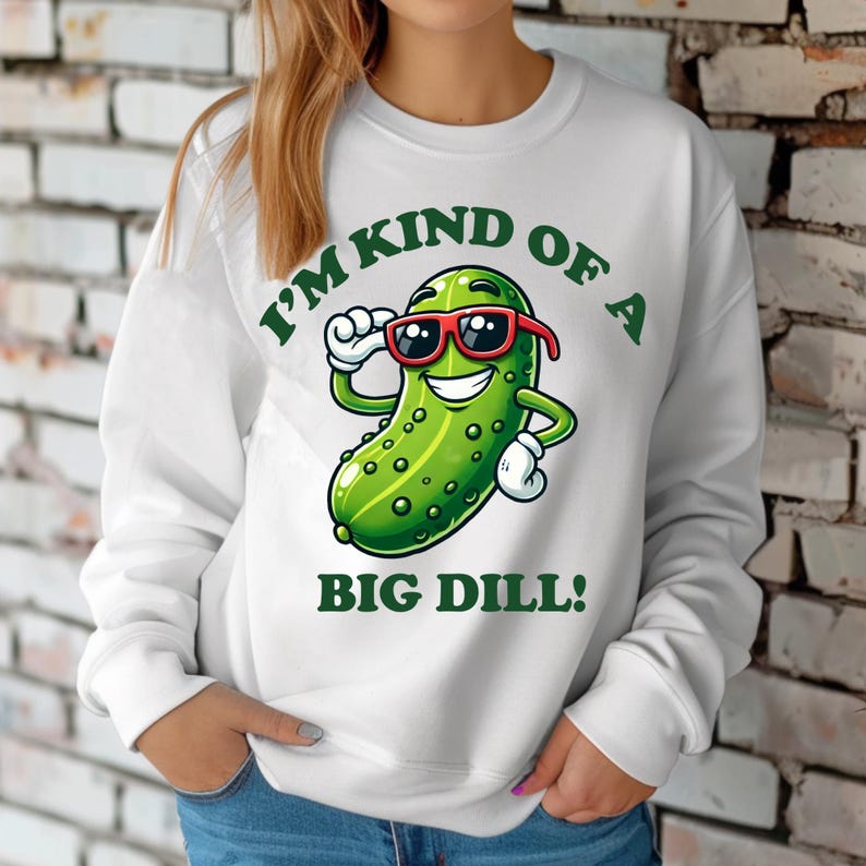 Może przedstawiać: Biała bluza z zielonym kresk&oacute;wkowym og&oacute;rkiem w okularach przeciwsłonecznych i tekstem "I'm kind of a big dill!"