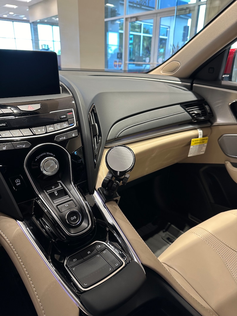 Puede incluir: Un interior de coche negro con un salpicadero negro y plateado y un asiento de cuero beige. El salpicadero tiene una pantalla t&aacute;ctil, una palanca de cambios y un panel de control con botones. El asiento est&aacute; hecho de cuero suave y flexible y tiene un patr&oacute;n de puntadas en forma de diamante.