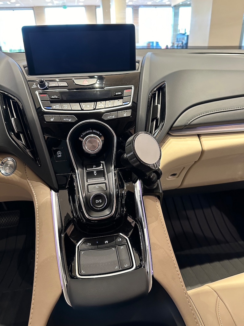 Puede incluir: Un interior de coche negro con una palanca de cambios negra y plateada, un panel de control negro y plateado y una pantalla negra y plateada. La pantalla est&aacute; en blanco. El coche tiene un interior de cuero beige.