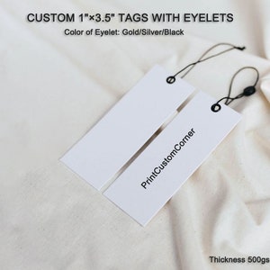 May include: Two white 1 inch by 3.5 inch hang tags with black eyelets and string. The tag on the right has the text "PrintCustomCorner" printed on it. The text "Thickness 500gsm" is printed at the bottom of the image.