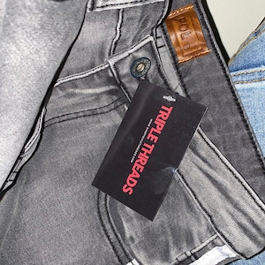 May include: Grey denim jeans with a brown leather patch that says "POLS" and a black tag that says "TRIPLE THREADS" www.triplethreads.com