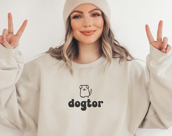 May include: A beige sweatshirt with a black graphic of a dog and the text "dogtor".