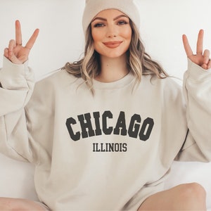 May include: A beige sweatshirt with the text "CHICAGO ILLINOIS" in black block letters.
