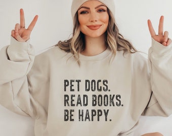 May include: A beige sweatshirt with the text "PET DOGS. READ BOOKS. BE HAPPY." printed in black on the front.