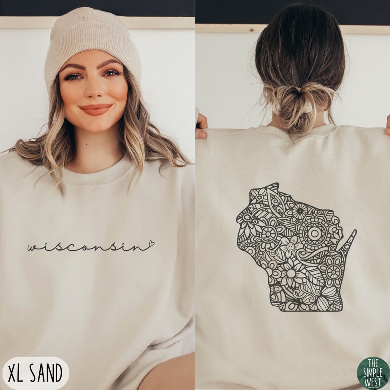 May include: A sand-colored sweatshirt with a black outline of the state of Wisconsin filled with a floral mandala design on the back. The front of the sweatshirt has the word "wisconsin" written in cursive with a small heart symbol. The sweatshirt is labeled "XL SAND".