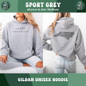 May include: Sport Grey Gildan unisex hoodie. The front features the text "north carolina" in a script font. The back displays a black, detailed outline of North Carolina. The hoodie is shown in size Medium.