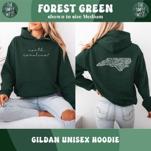 May include: Forest green Gildan unisex hoodie. The front features the text "north carolina" in white script. The back displays a white, detailed outline of North Carolina. The top banner reads "FOREST GREEN" and "shown in size Medium".
