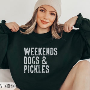 Op de afbeelding: Een donkergroen sweatshirt met de tekst "Weekends Dogs & Pickles" in wit. Het sweatshirt is een relaxed fit en heeft een ronde hals.