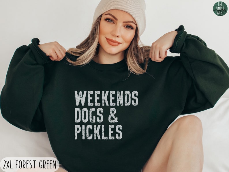 Op de afbeelding: Een donkergroen sweatshirt met de tekst "Weekends Dogs & Pickles" in wit. Het sweatshirt is een relaxed fit en heeft een ronde hals.