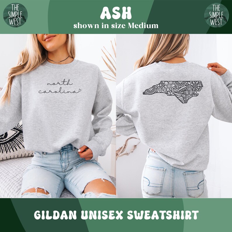 May include: Ash-colored Gildan unisex sweatshirt. The front features the script "north carolina". The back displays a detailed black design of the North Carolina state outline. The Simple West logo is visible. The sweatshirt is shown in size Medium.