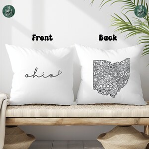 May include: Two white pillowcases with black text and a black and white outline of the state of Ohio. The front pillowcase says "ohio" with a small heart at the end. The back pillowcase has a detailed outline of the state of Ohio filled with black and white floral designs.