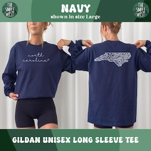 May include: Navy blue Gildan unisex long sleeve tee. The front features the cursive text "north carolina". The back displays a white, detailed outline of North Carolina. The shirt is shown in size Large.