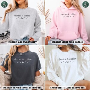 May include: Four different shirts with the text "doxies & coffee" and dachshund graphics. The shirts are a medium ash sweatshirt, a medium light pink hoodie, a medium pepper short sleeve tee, and a large white long sleeve tee.