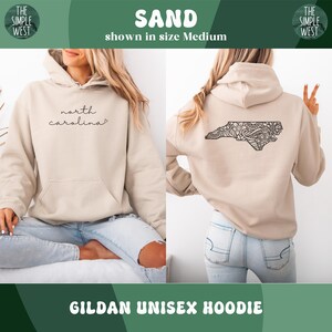 May include: Sand-colored Gildan unisex hoodie. The front features the script "north carolina". The back displays a detailed black outline of North Carolina with an intricate design. The hoodie is shown in size Medium.