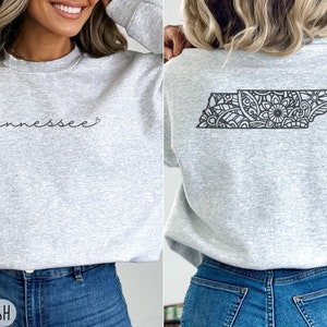 May include: A gray sweatshirt with the word "tennessee" in cursive on the front and a black and white mandala design of the state of Tennessee on the back.