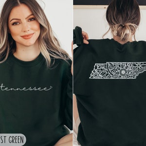 May include: A forest green sweatshirt with the word "Tennessee" and a heart on the front. The back of the sweatshirt features a white outline of the state of Tennessee filled with a floral mandala design.