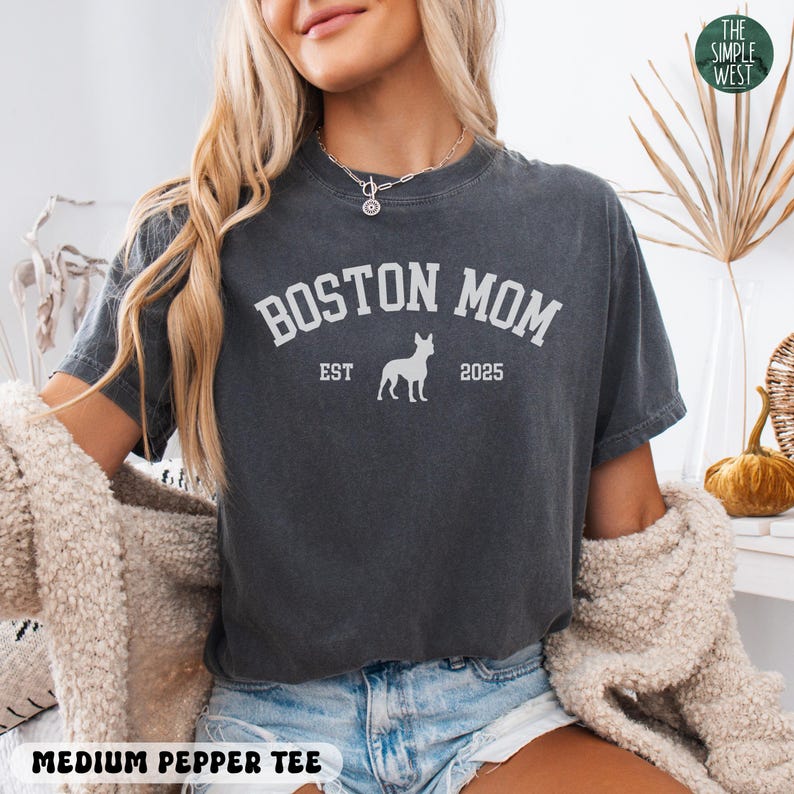 Puede incluir: Camiseta gris oscuro con el texto blanco "BOSTON MOM", una silueta de perro y "EST 2025". La camiseta es una "medium pepper tee".