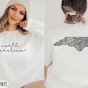 May include: White sweatshirt with the text "north carolina" on the front and a black and white outline of the state of North Carolina on the back.