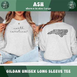 May include: Ash-colored Gildan unisex long sleeve tee. The front features the words "north carolina" in a script font. The back displays a black, detailed outline of North Carolina. The Simple West logo is in the top corners.