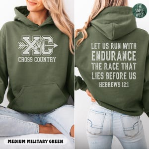 May include: An olive green hooded sweatshirt featuring a white graphic on the front with the text XC CROSS COUNTRY and a winged shoe icon. The back displays the white text LET US RUN WITH ENDURANCE THE RACE THAT LIES BEFORE US HEBREWS 12:1.