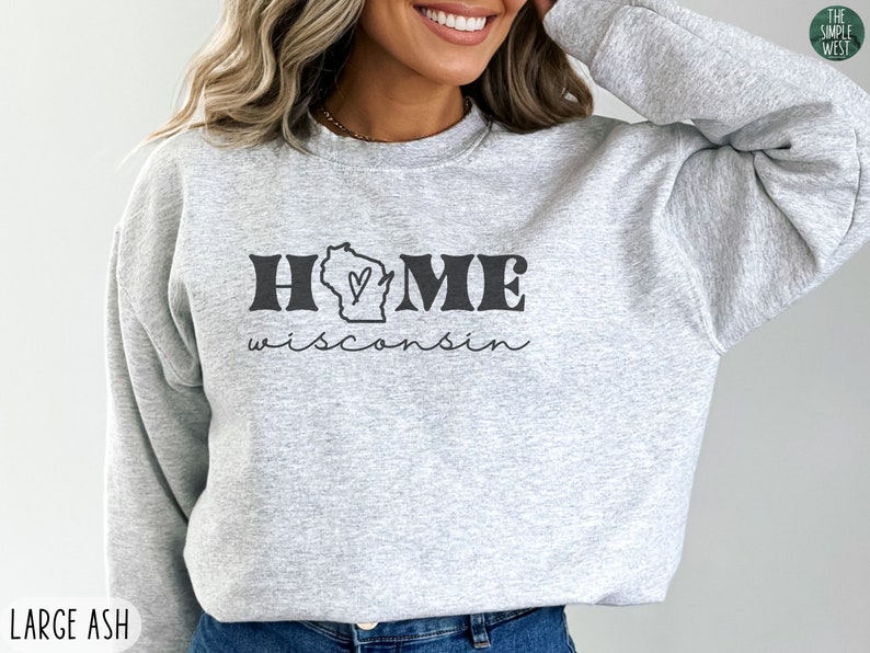 May include: Gray sweatshirt with the text "HOME wisconsin" in black. The word "HOME" has a stylized outline and a heart inside the letter "O". The state of Wisconsin is depicted inside the letter "O".