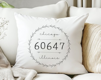 May include: White throw pillow with a black and white design featuring a wreath with the words "chicago 60647 illinois" inside.